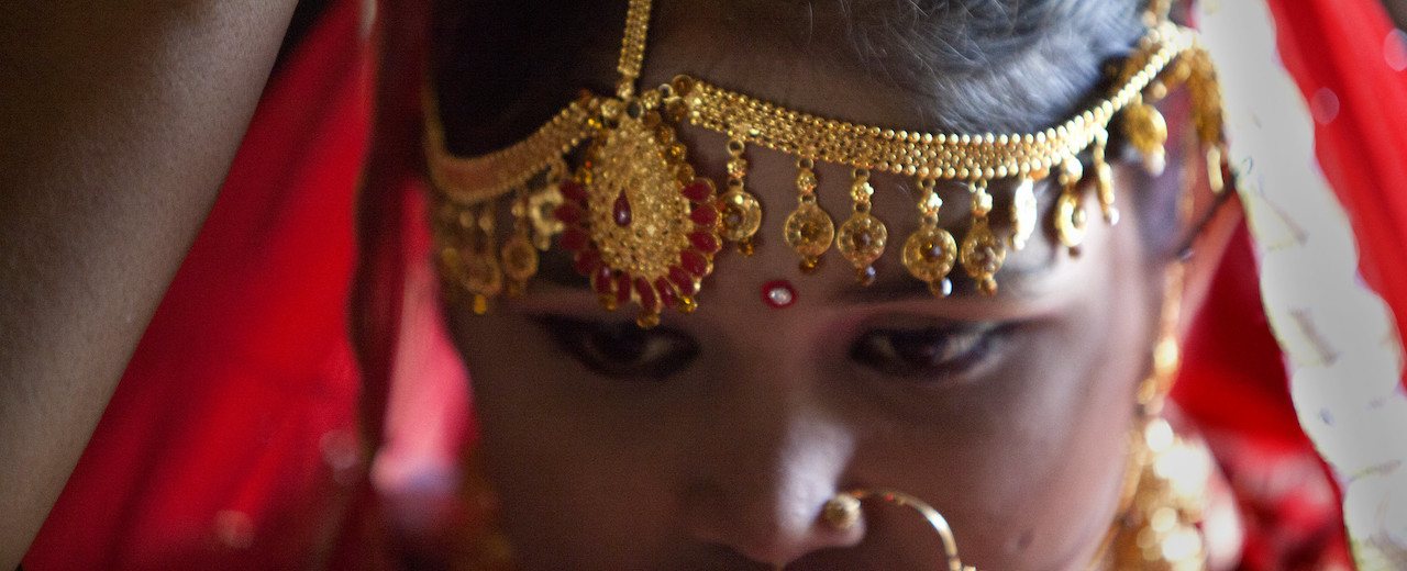 A young girl wears wedding jewelry.  