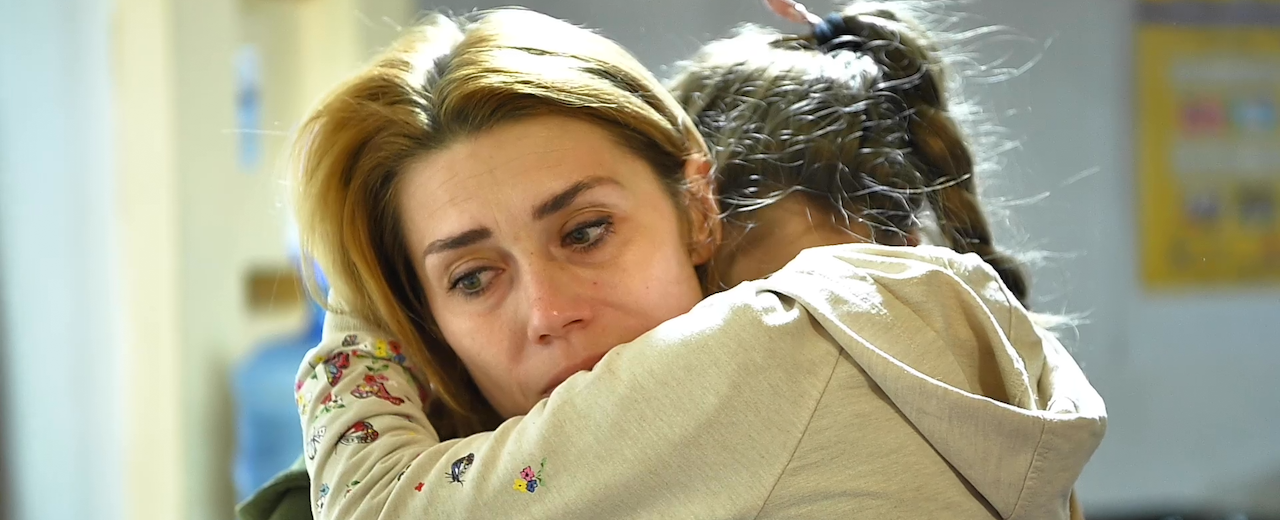 A young girl hugs a woman. 