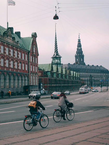 Cyclists riding along a wide embankment near historic buildings in Copenhagen city