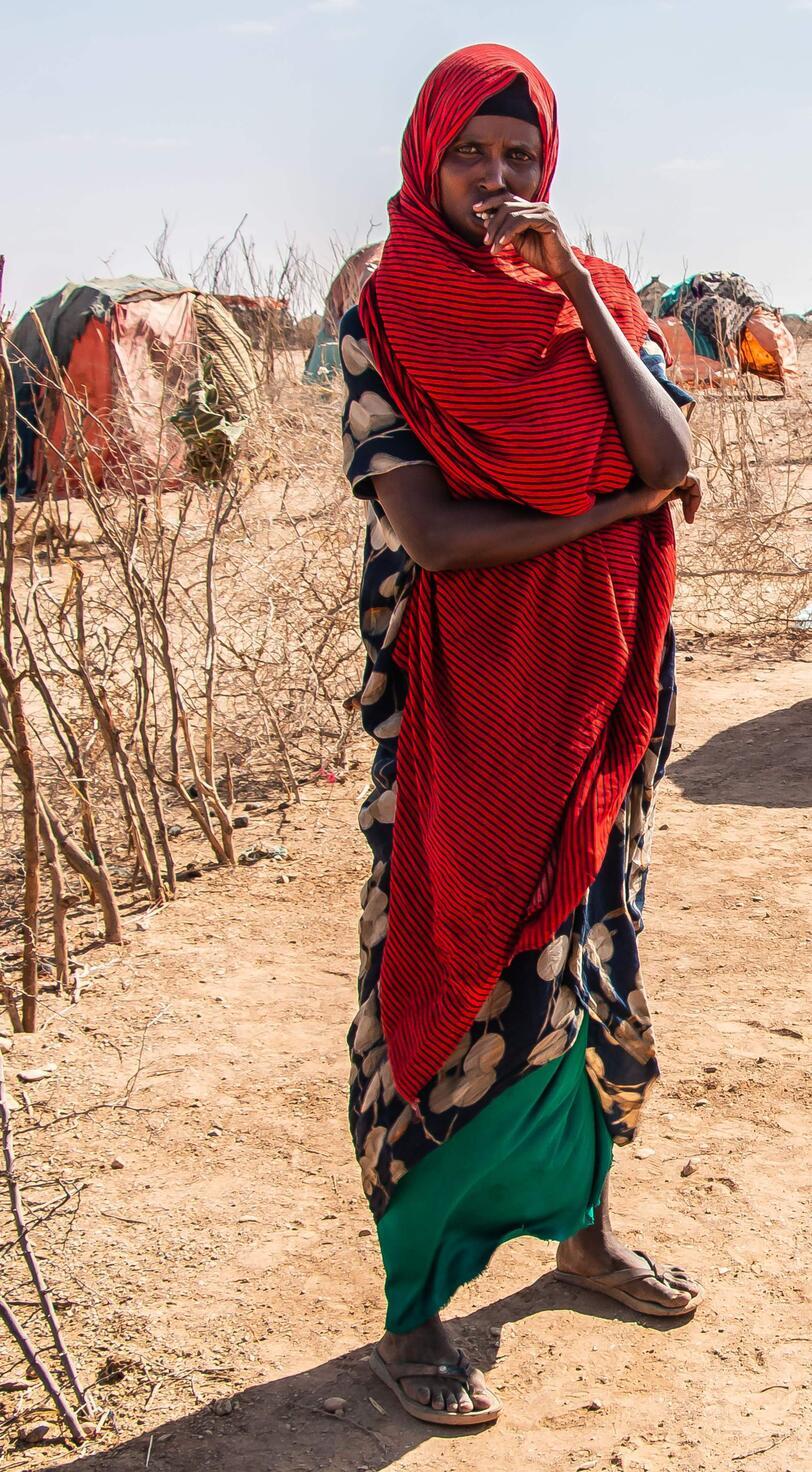 A woman and a small child stand in front of a tent.