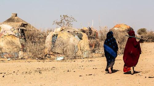 Two women walk in a desert.