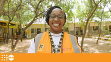 Jane, a female healthcare worker, smiles and wears an orange vest.