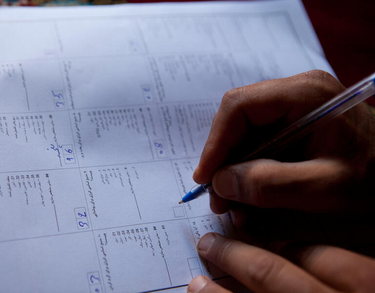Une main écrit sur un document de recensement.
