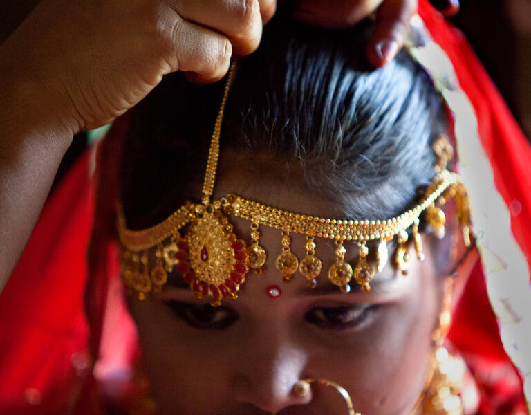 A young girl being dressed in decorative jewelry.