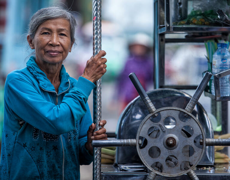 An older woman poses with machinery.