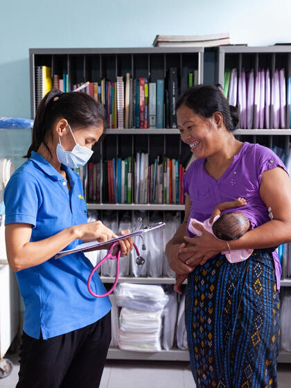 A woman breastfeeds and talks to a medical worker.
