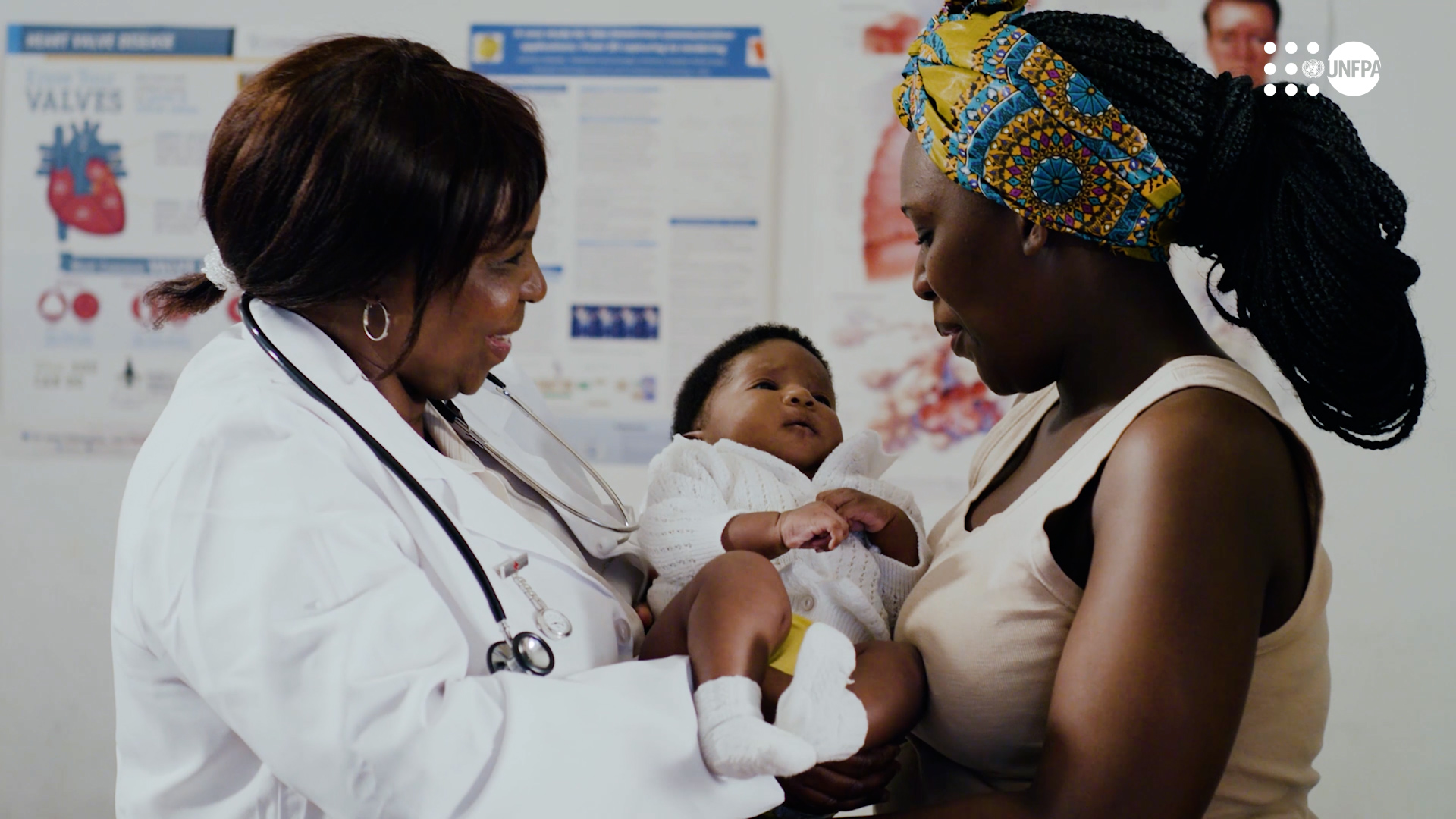 A nurse hands a baby to a mother.