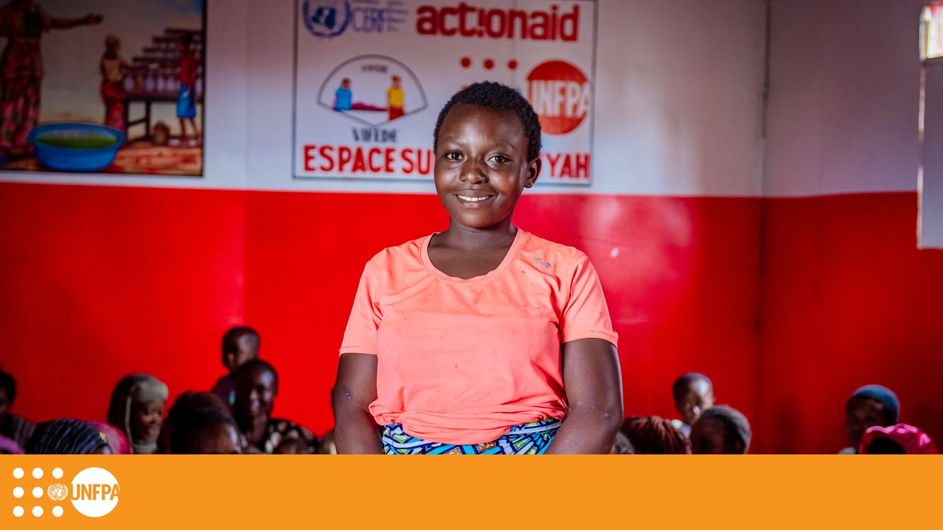 Young girl in pink t-shirt looks at camera and smiles